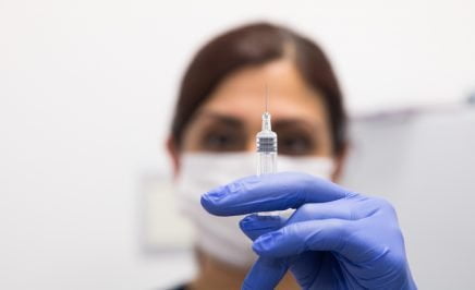 Young woman holding up a covid-19 vaccine