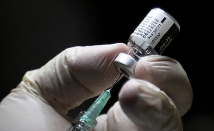 A closeup shot of a healthcare worker's gloved hands preparing to administer a vaccine.