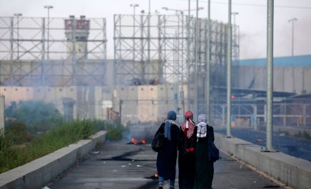 Three Palestinian protestors walk towards the border during a demonstration at the Erez crossing with Israel.