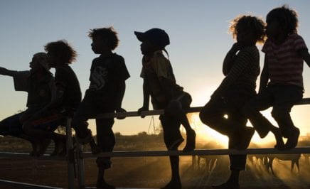 Silhouette of Indigenous children sitting on a fence