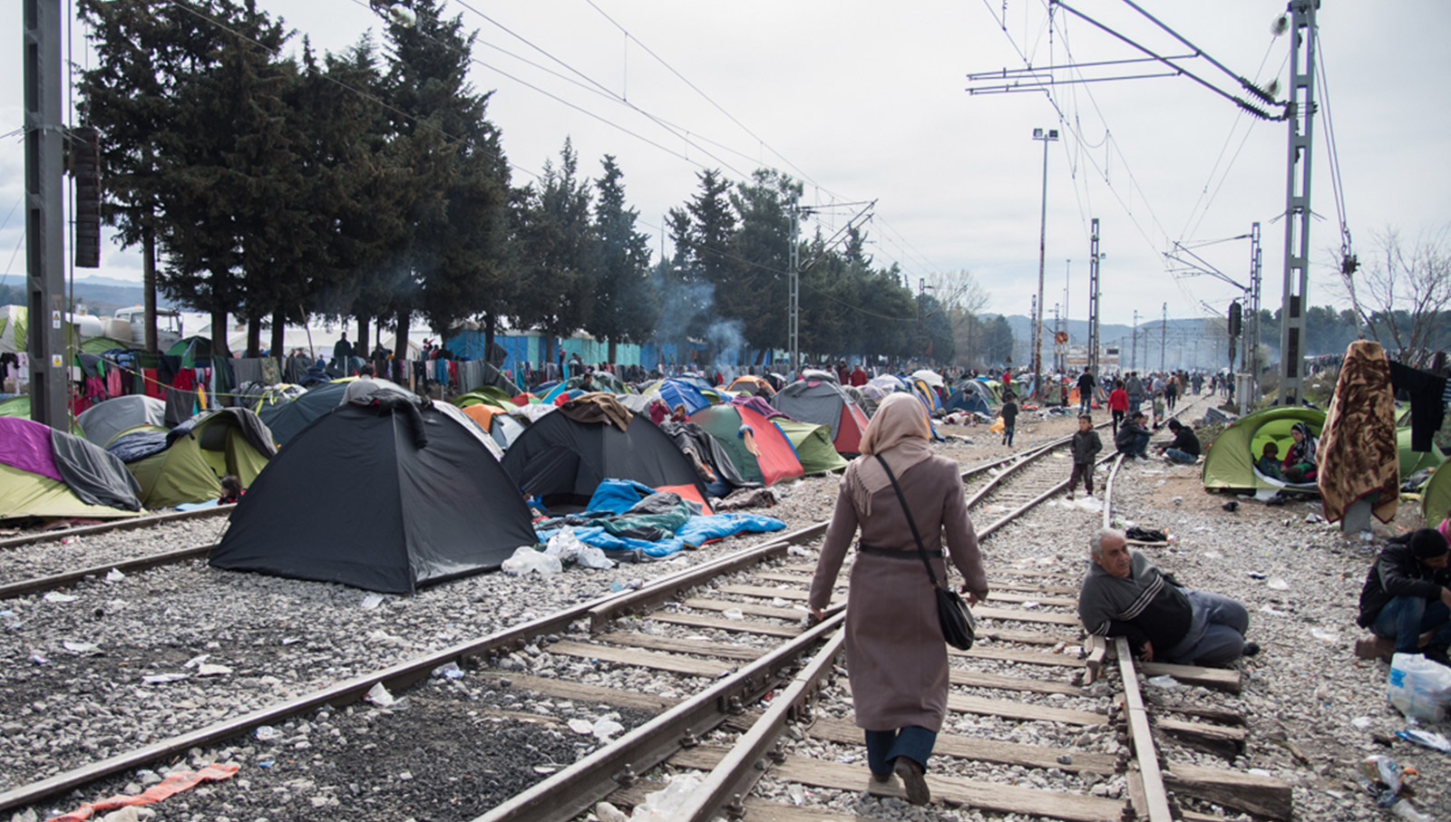 A woman walking through tents in a refugee camp