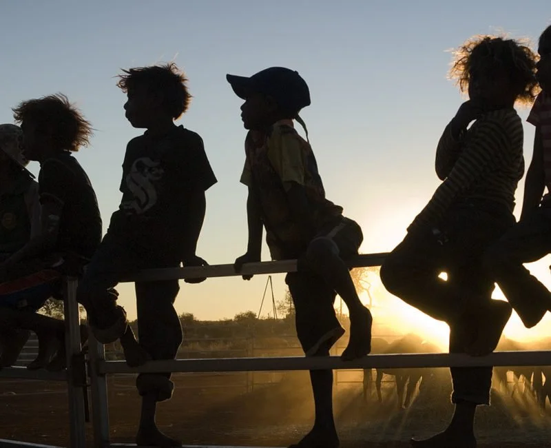 Silhouette of Indigenous children sitting on a fence