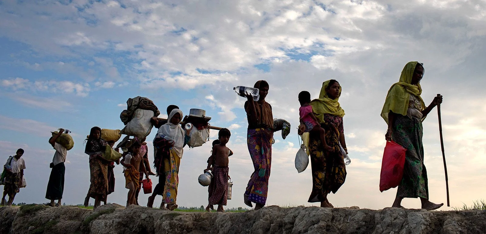 Rohingya refugees walk through a paddy field in Bangladesh